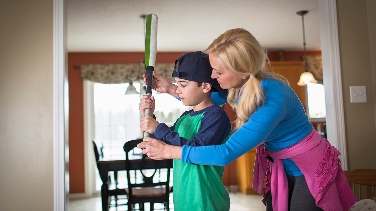 Mother teaching child to play baseball