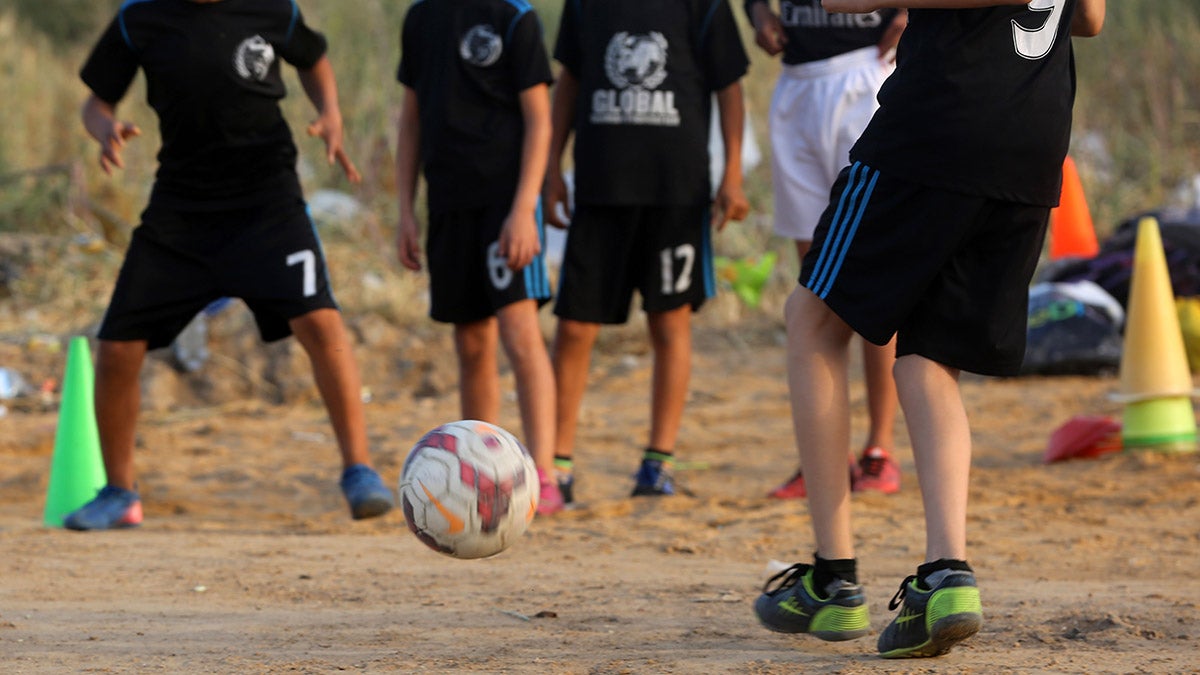 Children playing soccer in black uniforms for Soccer Without Borders