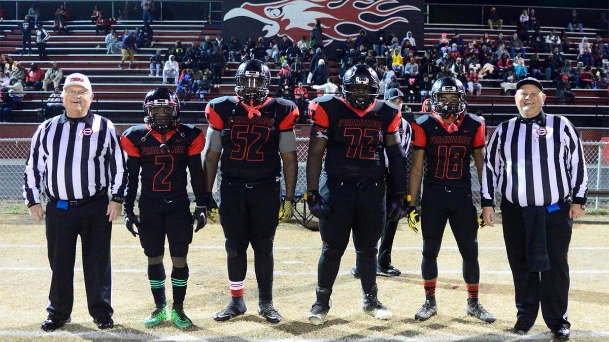 High school referees at football game with team and Chuck Morris