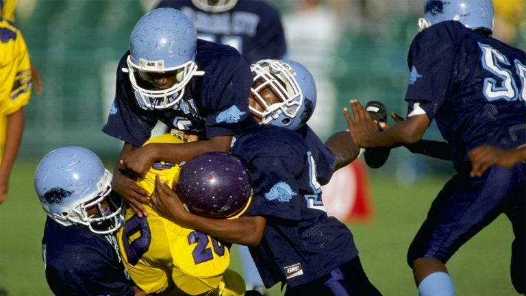 Five kids playing football and tackling